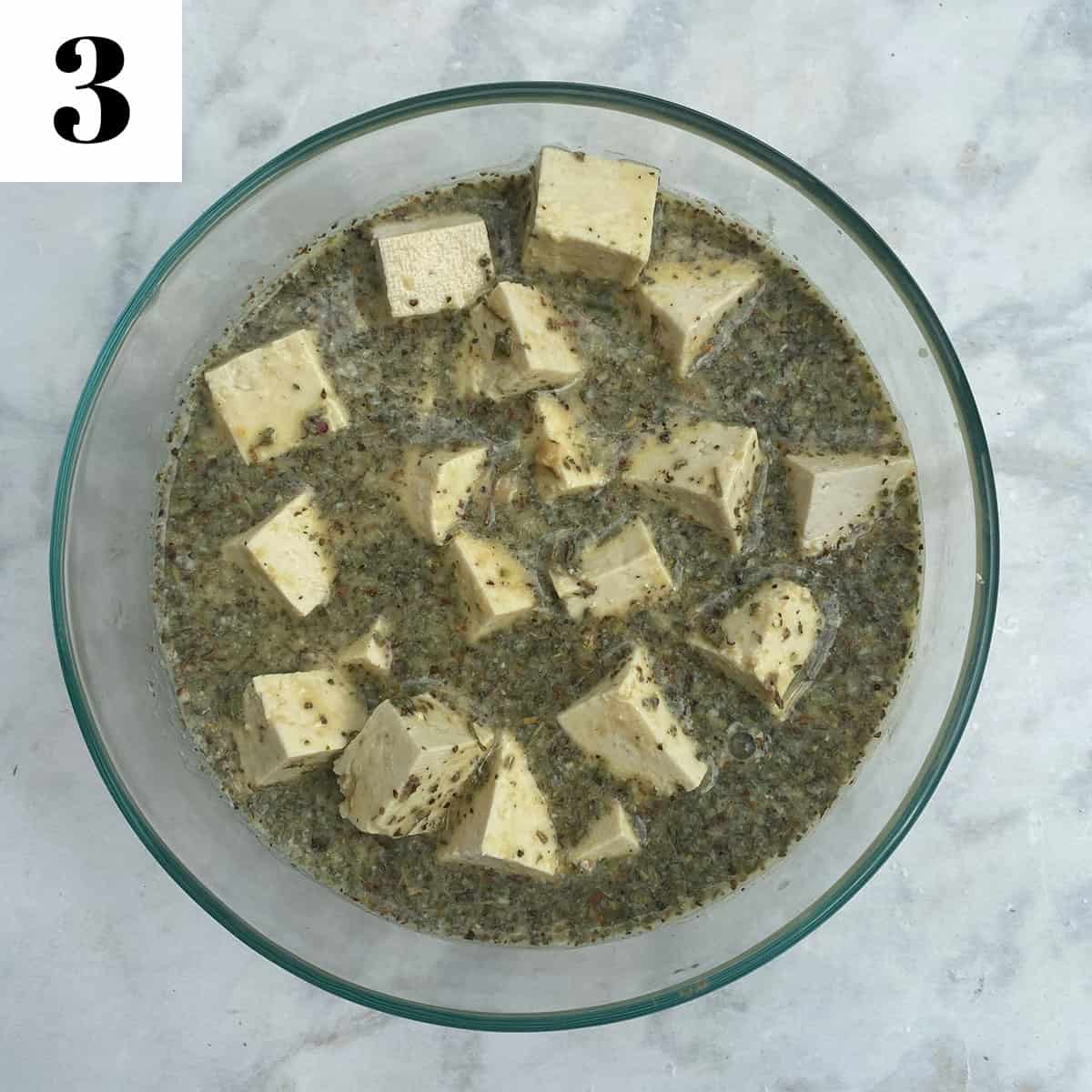 marinating tofu feta in glass bowl.