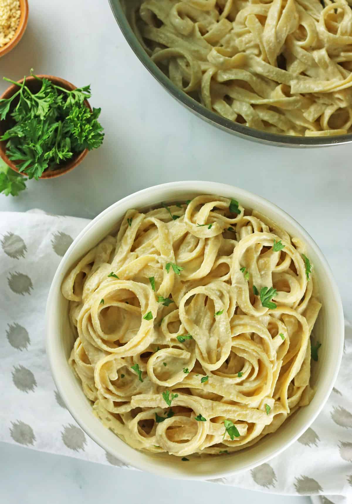 vegan cashew alfredo sauce in white bowl with parsley