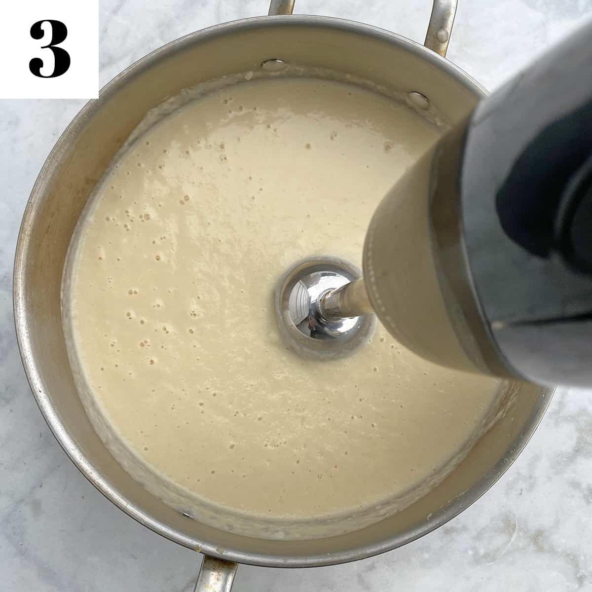 immersion blender blending sauce in large pan.