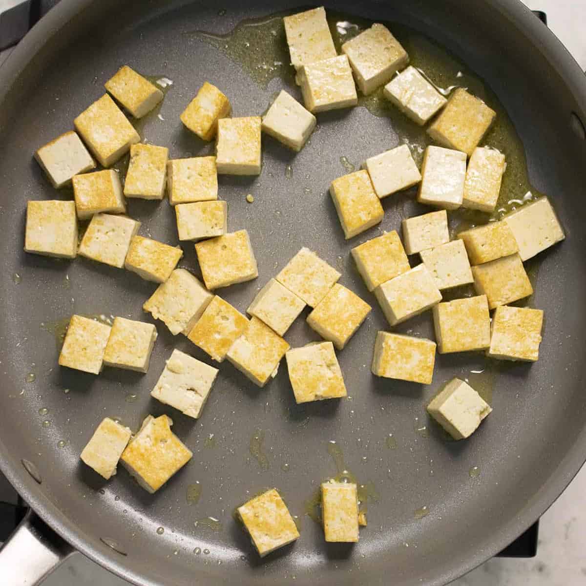 frying tofu squares in a pan with oil.