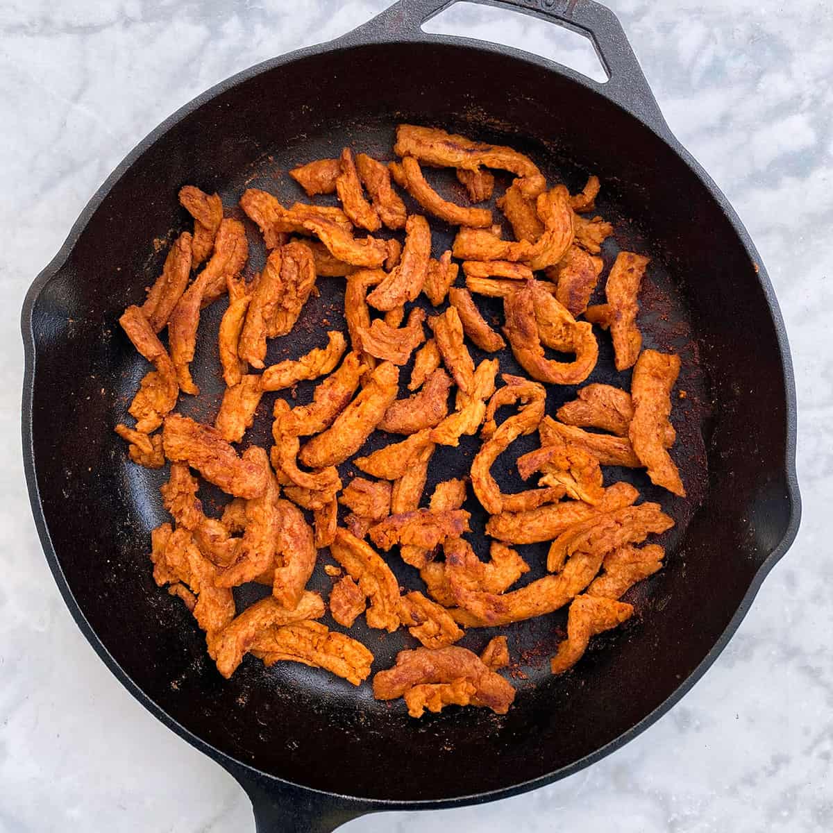 cooked bacon strips in cast iron pan.