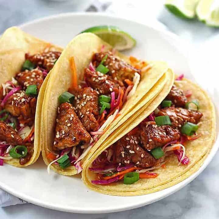 three tempeh tacos on white plate.